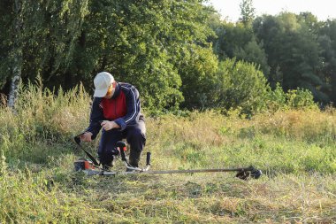 Adam çim biçme makinesiyle çalışıyor, çim biçiyor. Kopya alanı - Bahçe, doğa, yaz konsepti