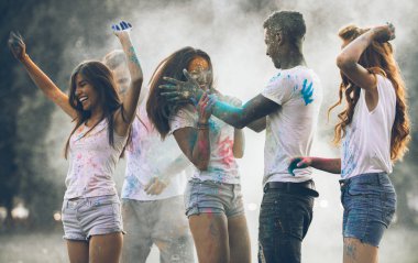 Group of teens playing with colors at the holi festival, in a park clipart