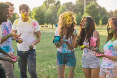 Group of teens playing with colors at the holi festival, in a park clipart