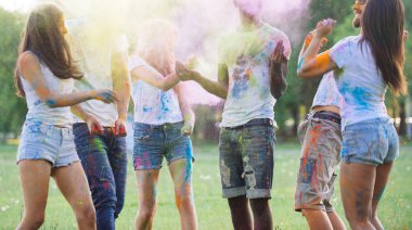 Group of teens playing with colors at the holi festival, in a park clipart