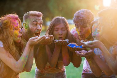 Group of teens playing with colors at the holi festival, in a park clipart