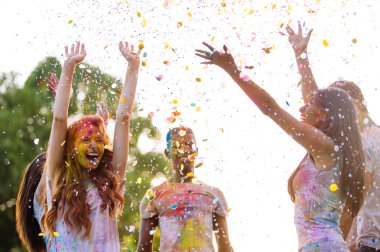 Group of teens playing with colors at the holi festival, in a park clipart