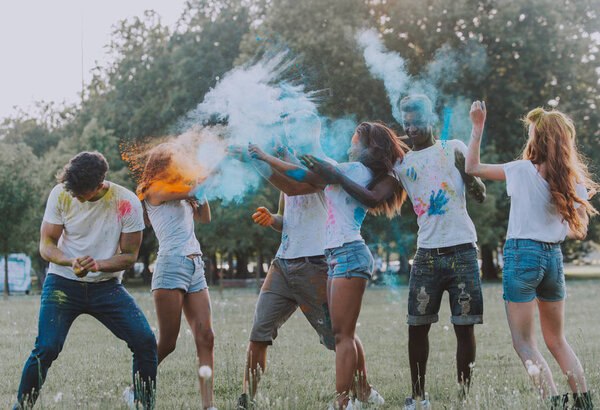 Группа подростков, играющих цветами на фестивале в Холи, в парке
