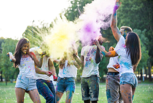 Group of teens playing with colors at the holi festival, in a park