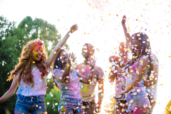 Group of teens playing with colors at the holi festival, in a park