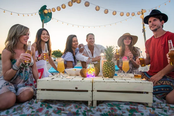 Group of friends having a picnic at the beach - Happy young people on a summer vacation at the beach