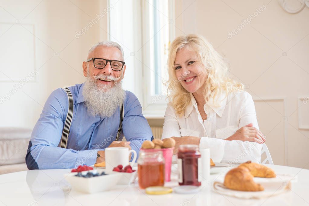 Happy senior couple having breakfast at home - Married couple on the 60's in their apartment, concepts about senority and relationship