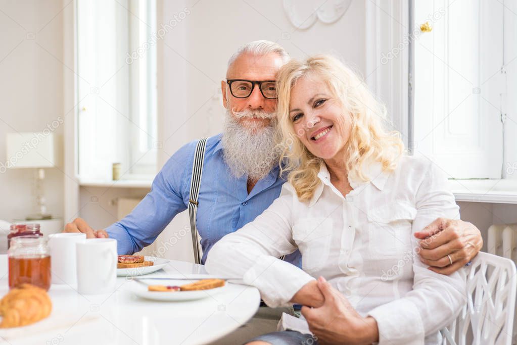 Happy senior couple having breakfast at home - Married couple on the 60's in their apartment, concepts about senority and relationship