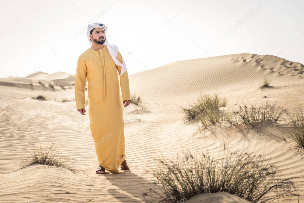 Handsome arabian man with traditional dress in the desert of Dubai