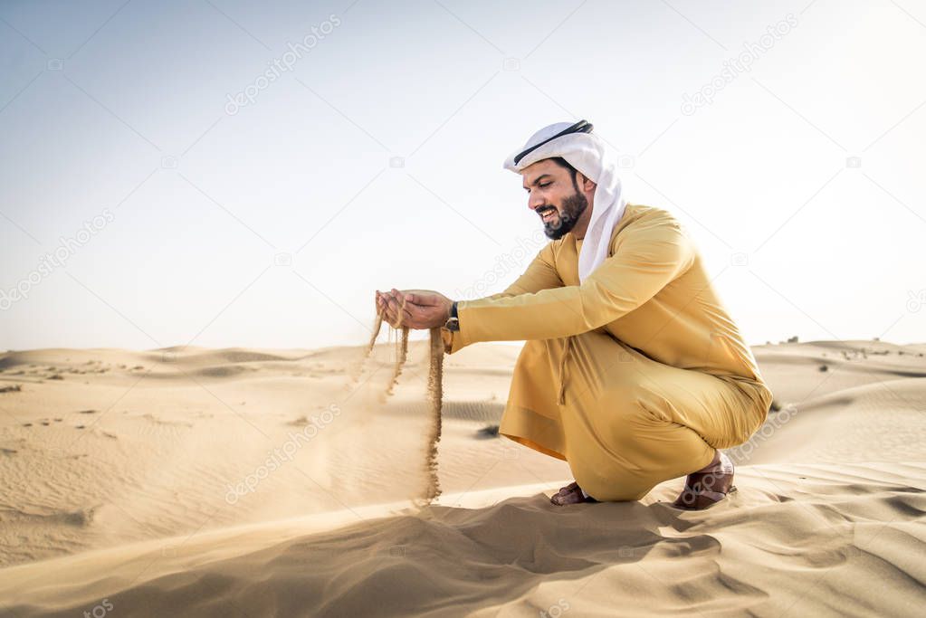 Handsome arabian man with traditional dress in the desert of Dubai