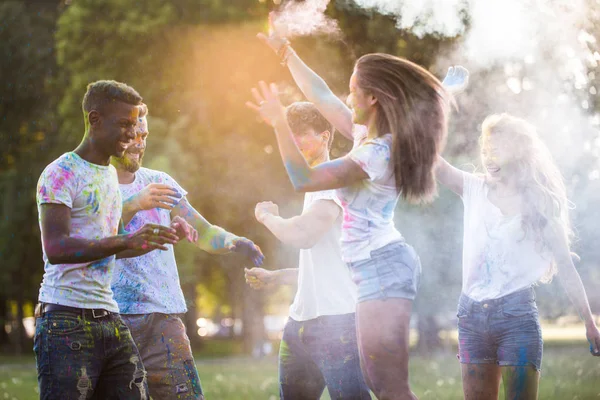一群快乐的朋友在公园里玩红颜色 年轻的成年人有乐趣在一个洒节 关于乐趣 乐趣和年轻一代的概念 — 图库照片