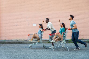 Çok etnik gruptan oluşan grup alışveriş sepetlerini bir park ile oynayan arkadaşıyla
