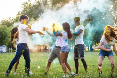 Holi ile oynarken mutlu arkadaş grubu bir parkta - Genç Yetişkin eğlenceli, eğlenceli ve genç nesil hakkındaki kavramları bir holi Festivali, eğleniyor renkler.