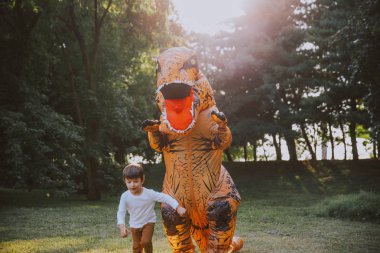 Baba ve oğul bir dinozor kostüm parkta oynarken açık aile ile eğleniyor