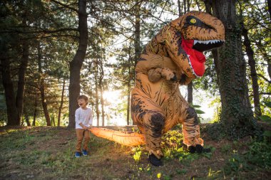 Baba ve oğul bir dinozor kostüm parkta oynarken açık aile ile eğleniyor
