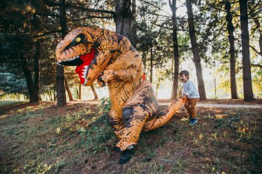 Baba ve oğul bir dinozor kostüm parkta oynarken açık aile ile eğleniyor