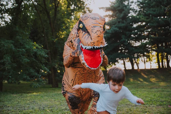 父と息子恐竜コスチュームで 公園で遊ぶ屋外の家族と一緒に楽しい時を過す — ストック写真