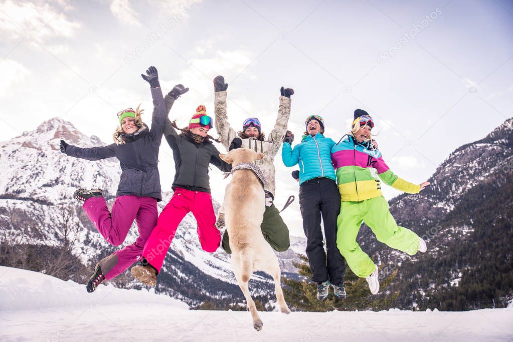 Happy group of people having fun on winter vacation - Friends witn snow suit partying outdoors