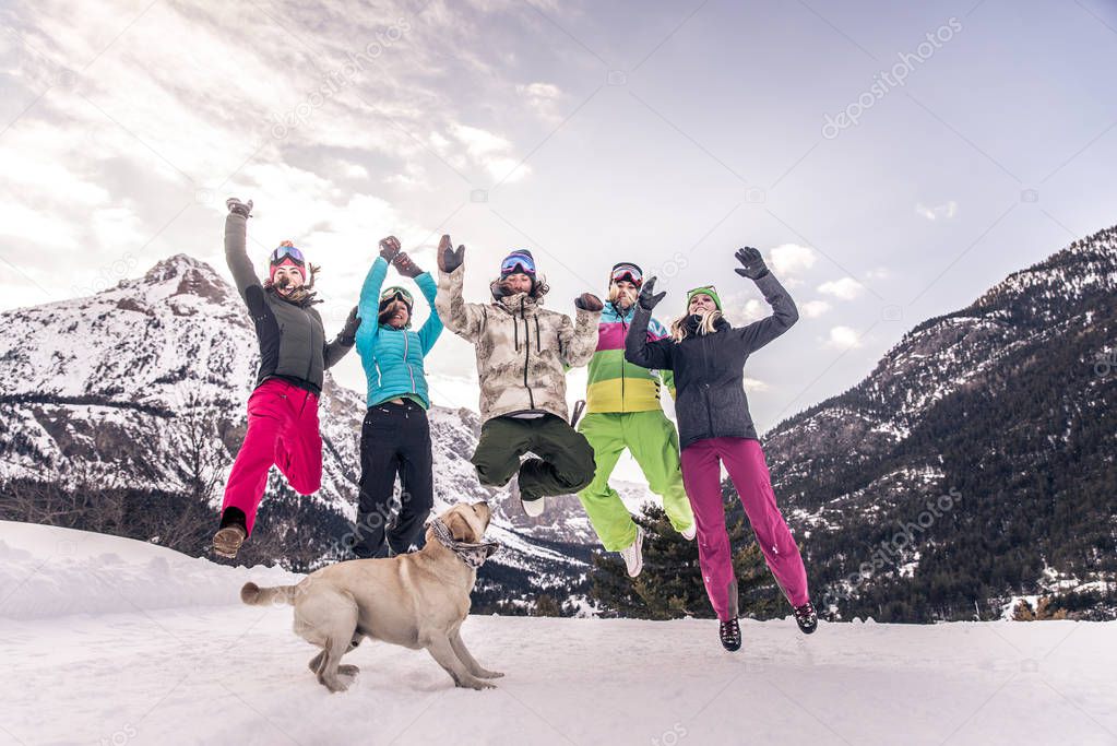 Happy group of people having fun on winter vacation - Friends witn snow suit partying outdoors