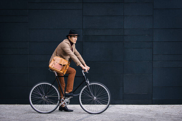 Молодой красивый мужчина в повседневной одежде за рулем велосипеда - портрет молодого студента, концепции бизнеса, мобильности и образа жизни
