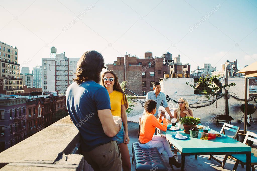 Group of friends apending time together on a rooftop in New york city, lifestyle concept with happy people