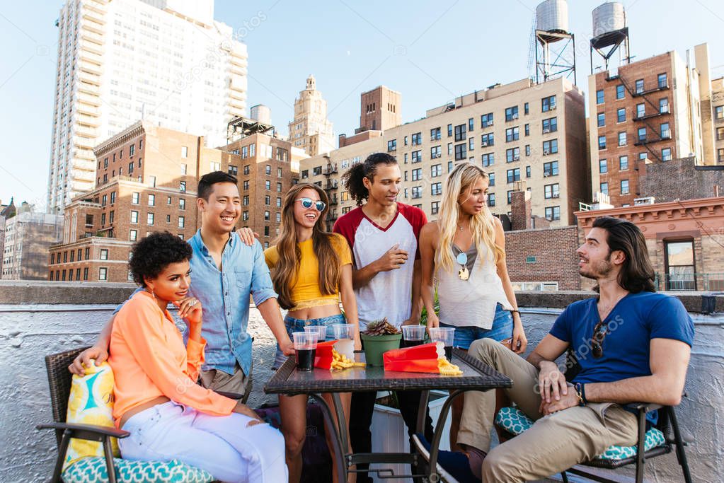 Group of friends spending time together on a rooftop in New york city, lifestyle concept with happy people