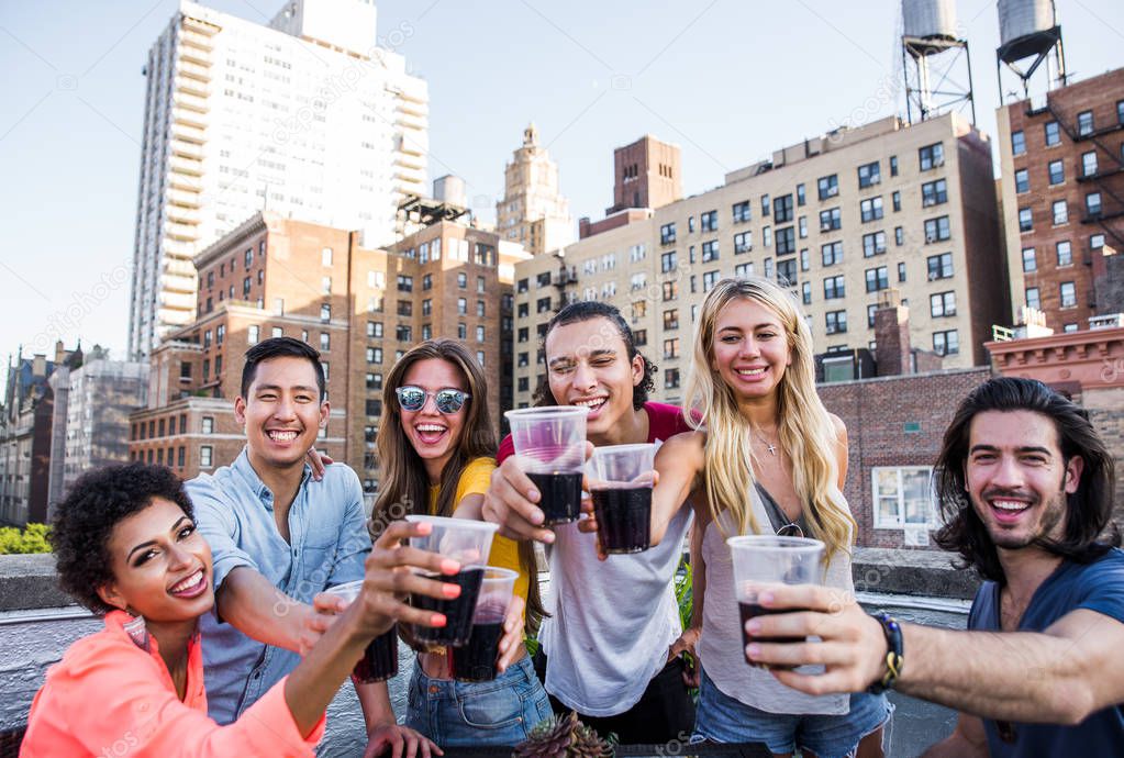 Group of friends spending time together on a rooftop in New york city, lifestyle concept with happy people