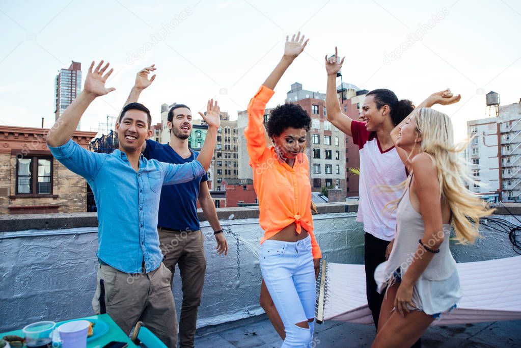 Group of friends spending time together on a rooftop in New york city, lifestyle concept with happy people