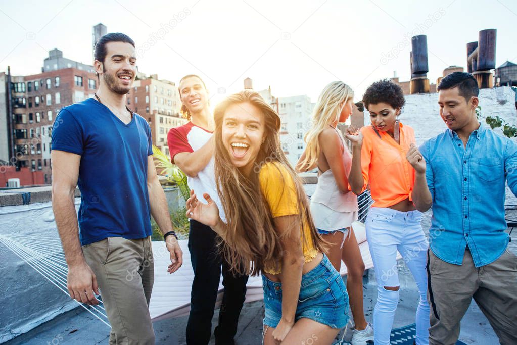 Group of friends spending time together on a rooftop in New york city, lifestyle concept with happy people