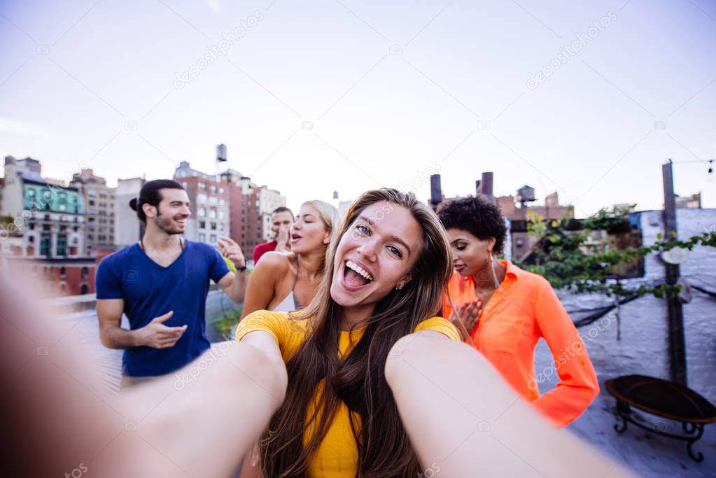 Group of friends spending time together on a rooftop in New york city, lifestyle concept with happy people