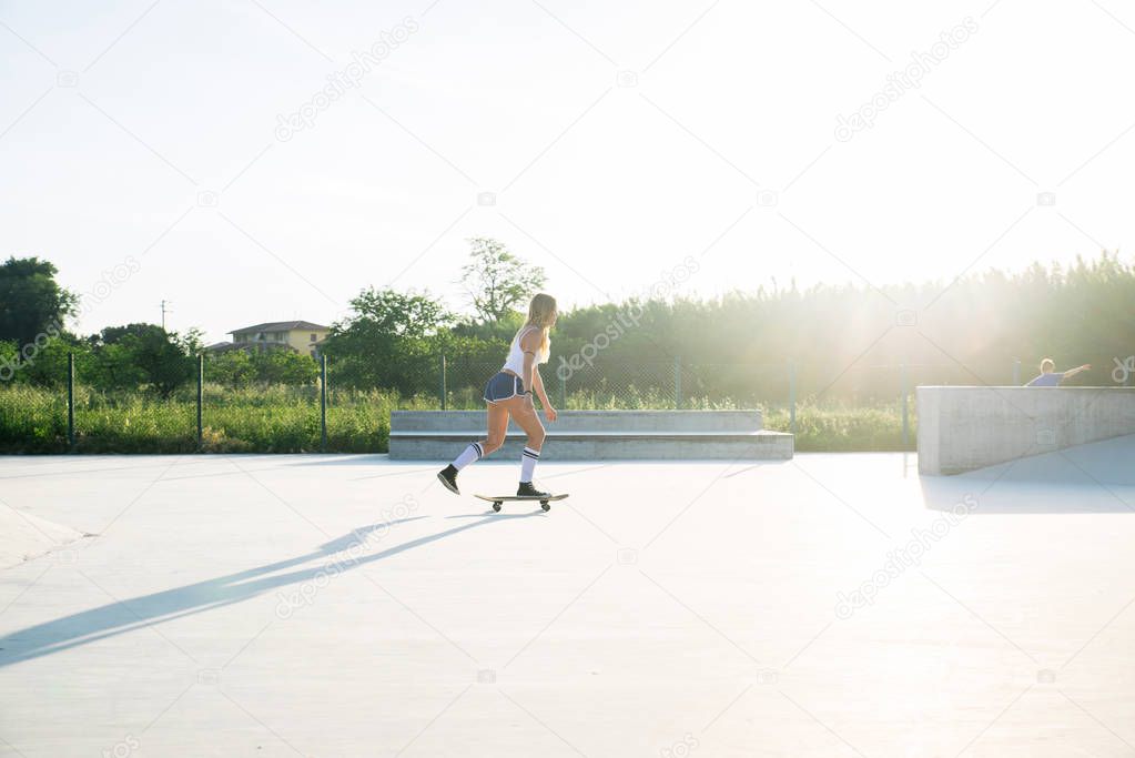 Stylish young woman skating outdoors - Pretty female skater playing with her skate