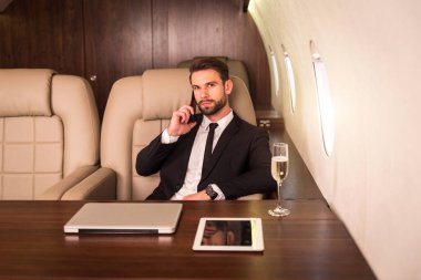 Businessman working while travelling on private jet - Portrait of business people taking a first class flight for work, concepts about business and mobility clipart