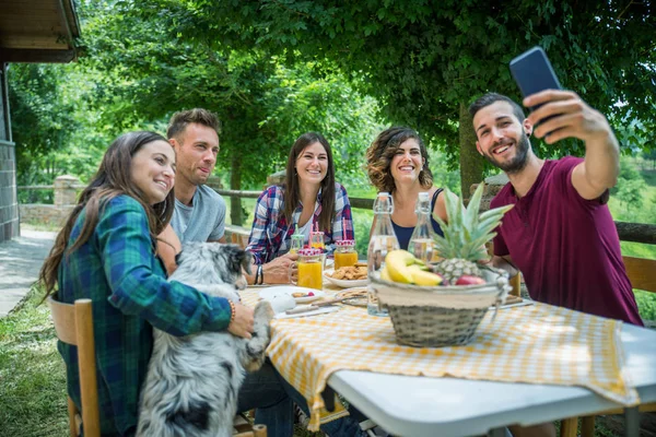 伝統的な田舎の庭で軽食を食べている友人に屋外の朝食をやって幸せな人々 のグループ — ストック写真