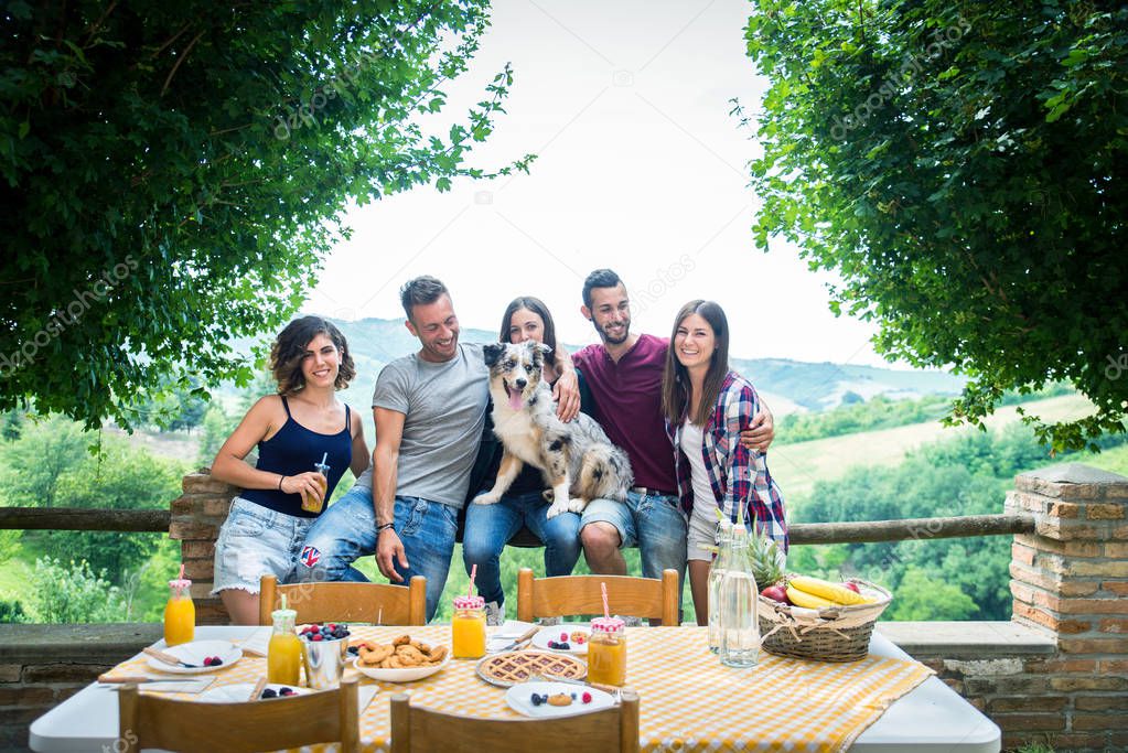 Group of happy people doing breakfast outdoors in a  traditional countryside - Friends eating snacks in the garden