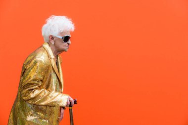 Komik ve savurgan üst düzey kadın renkli arka plan - genç yaşlı kadın altmışlı yıllarda eğleniyor ve parti poz