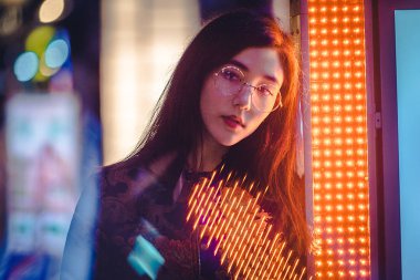 Açık havada, arka plan bulanık neon ışıkları ile poz güzel karışık ırk kadın