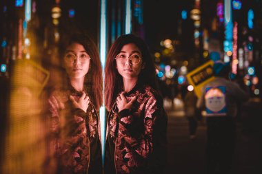 Açık havada, arka plan bulanık neon ışıkları ile poz güzel karışık ırk kadın