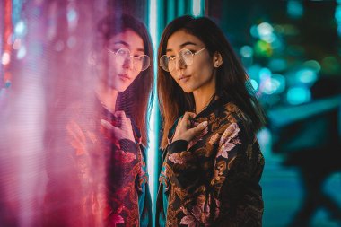 Açık havada, arka plan bulanık neon ışıkları ile poz güzel karışık ırk kadın