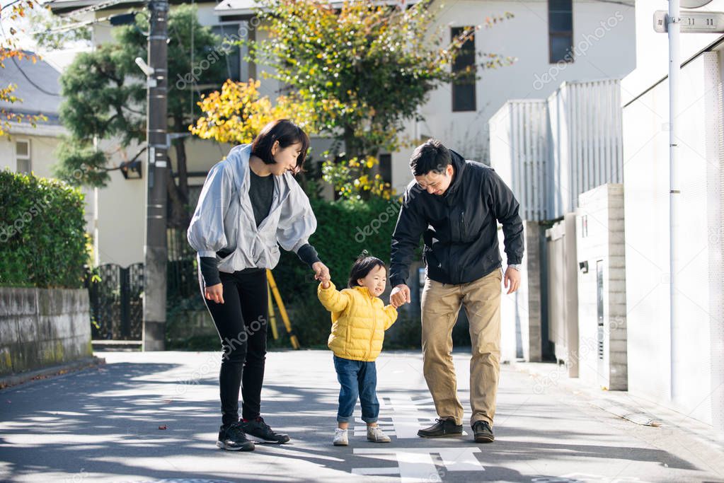 Happy and playful japanese family with small cute daughter having fun outdoors