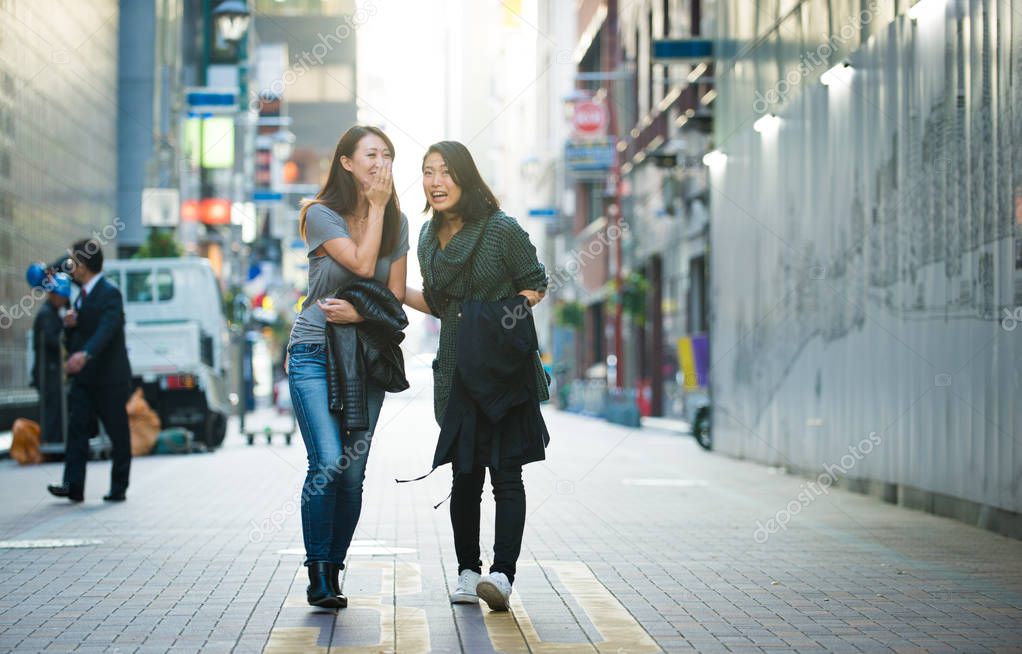 Two girlfriends meeting outdoors and having fun - Japanese people bonding on Tokyo streets