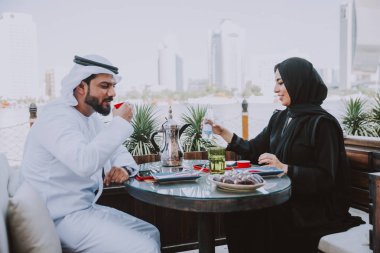 Mutlu çift Dubai'de zaman harcama. bir kafede sohbet geleneksel kıyafetlerle kadın ve erkek