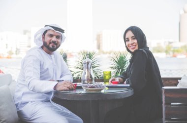 Mutlu çift Dubai'de zaman harcama. bir kafede sohbet geleneksel kıyafetlerle kadın ve erkek