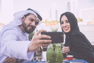 Mutlu çift Dubai'de zaman harcama. bir kafede sohbet geleneksel kıyafetlerle kadın ve erkek