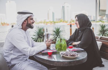 Mutlu çift Dubai'de zaman harcama. bir kafede sohbet geleneksel kıyafetlerle kadın ve erkek