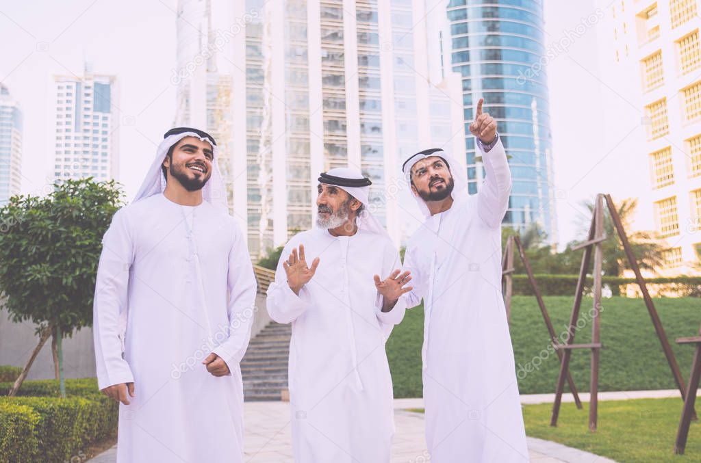 Three business men walking in Dubai wearing traditional emirati clothes