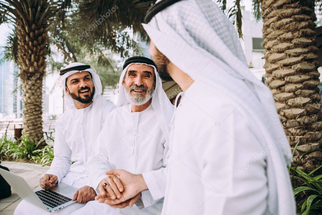 Three business men walking in Dubai wearing traditional emirati clothes