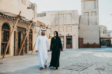 Mutlu çift Dubai'de zaman harcama. erkek ve kadın geleneksel kıyafetlerle eski şehirde alışveriş yapma
