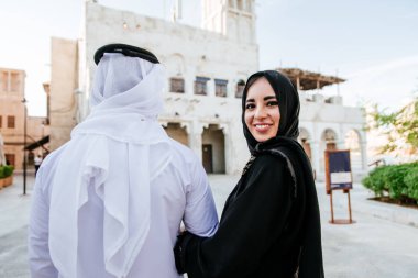 Mutlu çift Dubai'de zaman harcama. erkek ve kadın geleneksel kıyafetlerle eski şehirde alışveriş yapma