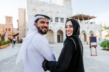 Mutlu çift Dubai'de zaman harcama. erkek ve kadın geleneksel kıyafetlerle eski şehirde alışveriş yapma