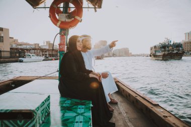 Mutlu çift Dubai'de zaman harcama. Nehrin üzerinde bir seyir alarak geleneksel kıyafetlerle kadın ve erkek